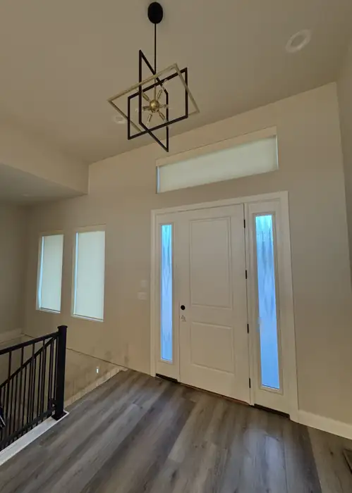 White shades over tall windows beside the front door and stairway.