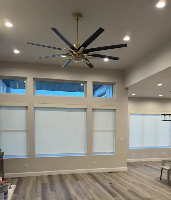 White roller shades across the lower windows of a tall, open living space.