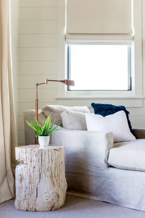 White Roman shade above a light sofa with blue and white pillows.