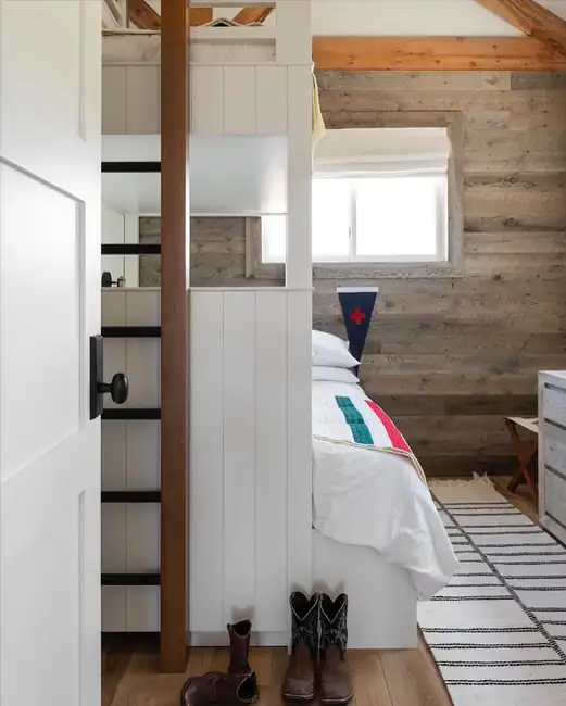 White Roman shade over a window in a rustic bedroom.